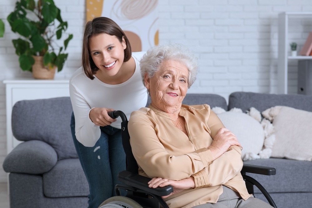 Smiling senior woman in wheelchair with nurse at home
